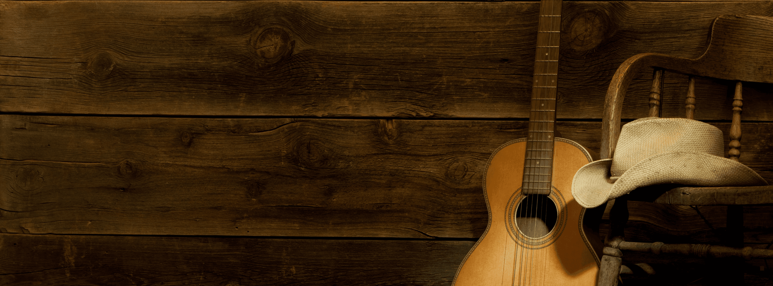 A guitar and a worn hat resting together in warm light