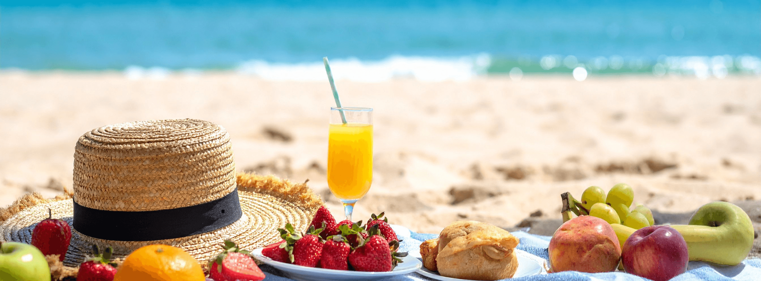 A summer picnic of fruit and juice on a cloth by the sea